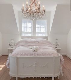 a dog laying on top of a white bed in a room with chandelier