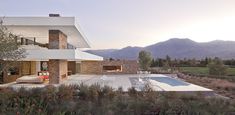 a modern house with a pool in the foreground and mountains in the back ground