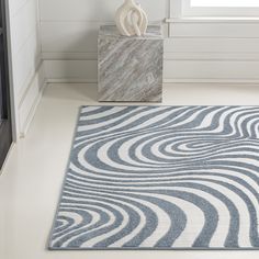 a white and blue rug with wavy lines on it in a room next to a window