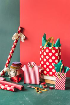 some wrapping paper, scissors and other items are sitting on a table next to a red wall