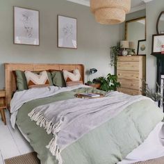 a bedroom with a bed, dressers and pictures hanging on the wall above it