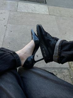 a person sitting on the ground with their feet up wearing black shoes and blue jeans