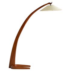 a wooden floor lamp with a white shade on it's head and an oval base