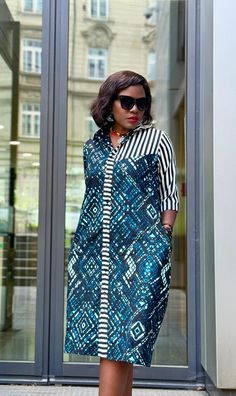 Step out in style with this stunning African Print Shirt Dress, a perfect blend of tradition and modernity. Crafted from high-quality fabric, this dress features a vibrant geometric pattern in rich blue and black tones, beautifully contrasted by bold black-and-white stripes on the upper bodice and along the button placket. The three-quarter length sleeves add a touch of elegance, making it suitable for both casual outings and more formal occasions. Designed for the fashion-forward woman, this dr African Traditional Dresses Modern, Modern African Dresses, Modern African Clothing, African Print Shirt, African Outfits, Short African Dresses, Ankara Gown, African Dresses Modern, Print Shirt Dress