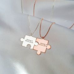 two pieces of the same puzzle are shown on a white satin surface with gold chains