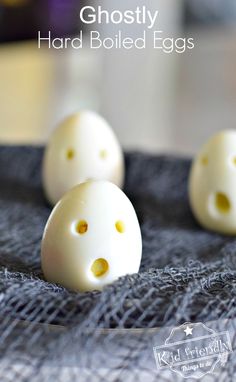 three white eggs with yellow dots on them are sitting on a gray cloth and the words, ghostly hard boiled eggs