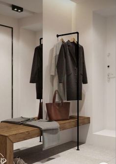 a white bathroom with a wooden bench and coat rack