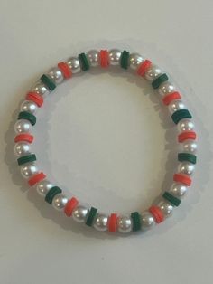 a white bracelet with red, green and orange beads on it's end is shown