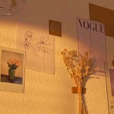 a vase filled with flowers sitting on top of a table next to pictures and posters