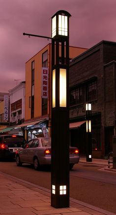 a tall clock tower sitting on the side of a road next to traffic at night