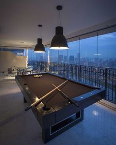 a pool table in the middle of a room with two lights hanging from it's ceiling