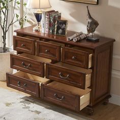 a wooden dresser with drawers and pictures on the wall