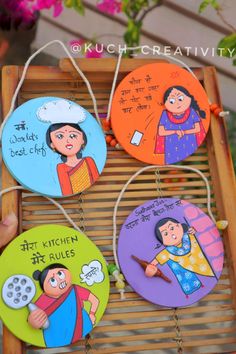 four colorfully painted magnets hanging on a bamboo board with flowers in the background