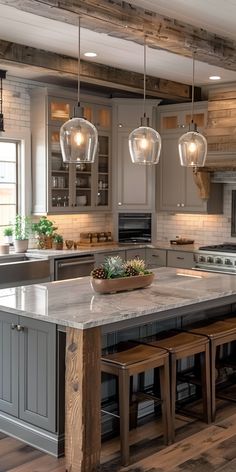 a kitchen with an island and stools in front of the counter top, lights hanging from the ceiling