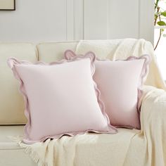 two pink pillows sitting on top of a white couch