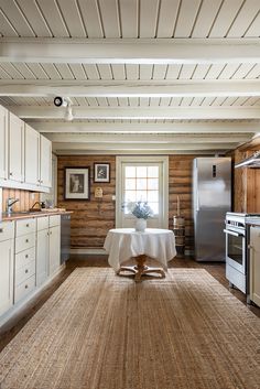 a kitchen with white cabinets and an area rug on the floor that has a table in it