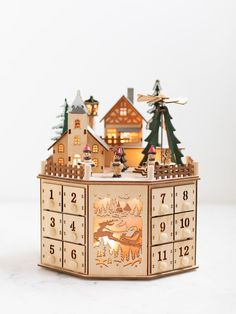 a wooden clock with houses and trees on the top is shown in front of a white background