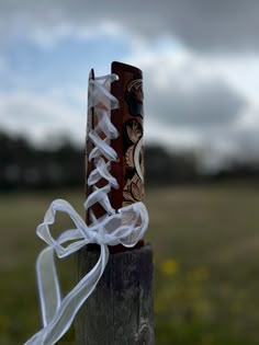 two wooden poles with ribbons tied to them in front of a grassy field and sky