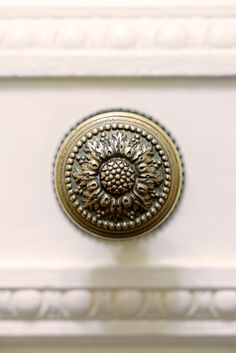 an ornate brass door knob on a white cabinet