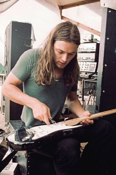 a man with long hair is playing an electric guitar