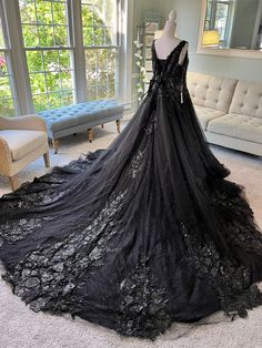 a black dress is on display in a room with couches and windows behind it