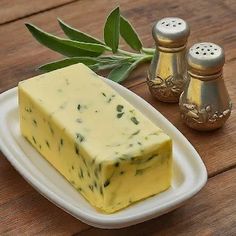 a piece of cheese sitting on top of a white plate next to salt and pepper shakers