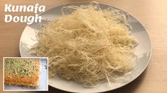 a white plate topped with lots of food next to a pile of noodles on top of a wooden table