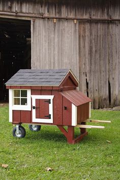 a small red and white chicken house on wheels