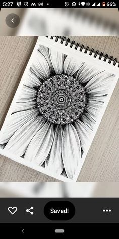 a black and white drawing of a sunflower on a wooden table next to a cell phone