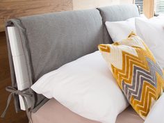 a couch with pillows on top of it in front of a bed headboard and window