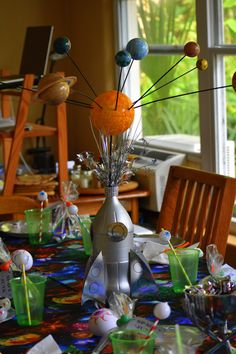 a table topped with an orange and silver vase filled with flowers on top of it