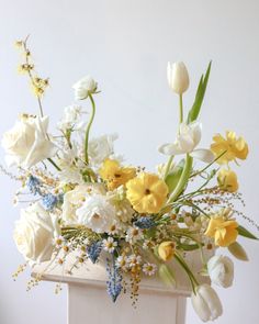 a vase filled with lots of white and yellow flowers