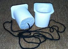 two white cups sitting on the floor next to a black cord and a brown carpet