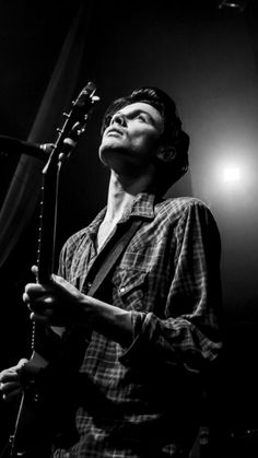 a man standing in front of a microphone with his eyes closed and holding a guitar