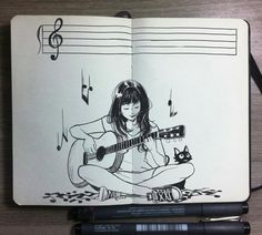 an open notebook with a drawing of a girl playing the guitar