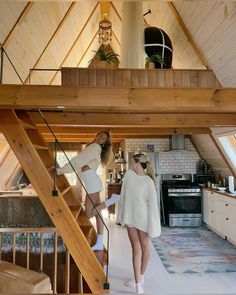 two women are standing in the kitchen and looking at something on the floor below them