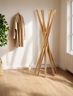 a coat rack in the corner of a room next to a potted plant and jacket hanger