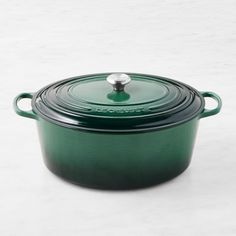 a green casserole with a lid on a white tablecloth and a gray background