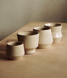 four white cups sitting on top of a wooden table