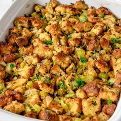 a white casserole dish filled with stuffing and green onions, topped with parsley