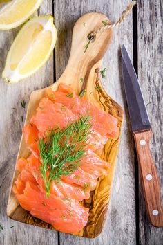 salmon on a cutting board with lemons and a knife