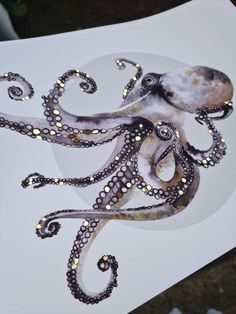 an octopus is sitting on top of a white plate with gold dots in it's tentacles