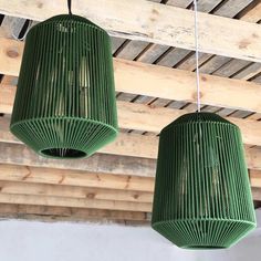 two green lamps hanging from a wooden ceiling