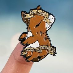 a hand holding a pin with a bear on it