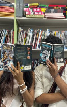 two people reading books in front of a book shelf