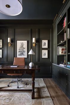 a home office with black walls and wooden flooring, along with bookshelves