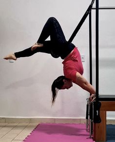 a woman doing a handstand on a pink mat