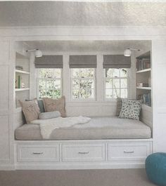 there is a white couch with pillows on it in the room that has built - in bookshelves