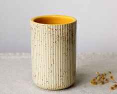 a yellow and white vase sitting on top of a table next to a flower pot