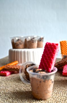 two cups filled with different types of desserts on top of a cloth covered table